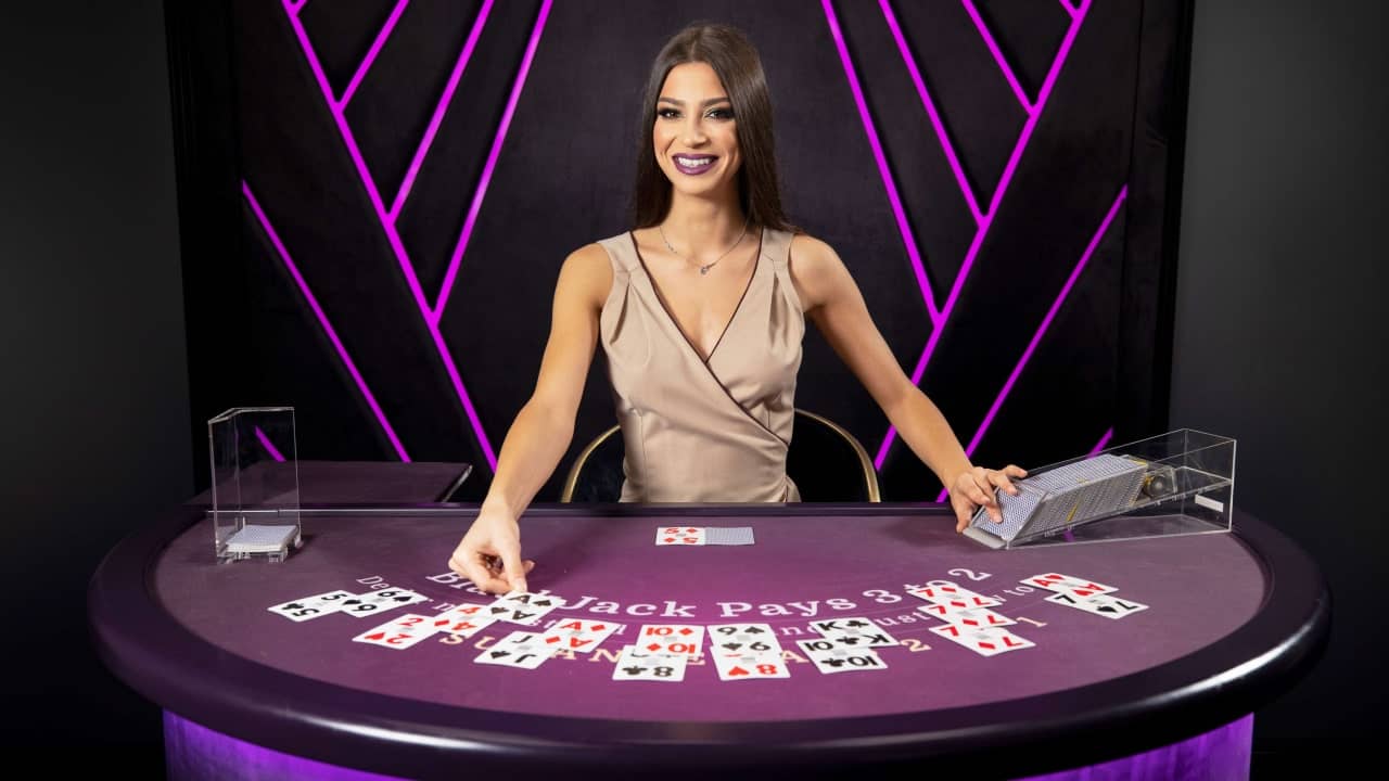 Live casino Blackjack dealer smiling and delaing cards on the blackjack table